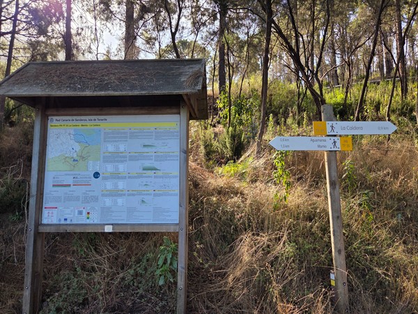 Cartel informativo y señalización de senderos en la zona de Aguamansa, Tenerife, indicando rutas hacia La Caldera y Mamio en medio del bosque.
