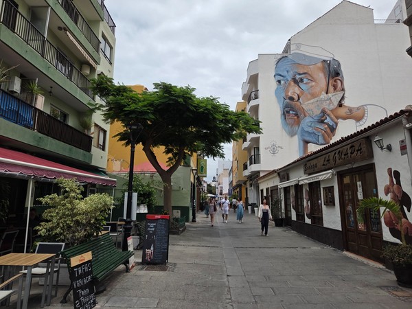 Calle peatonal del barrio de La Ranilla con un mural artístico y restaurantes locales en el Puerto de la Cruz.