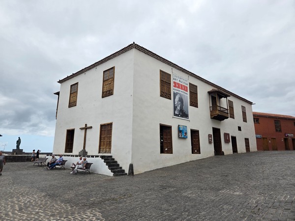 Fachada blanca de la Casa de la Real Aduana y Museo de Arte Contemporáneo junto a la plaza.
