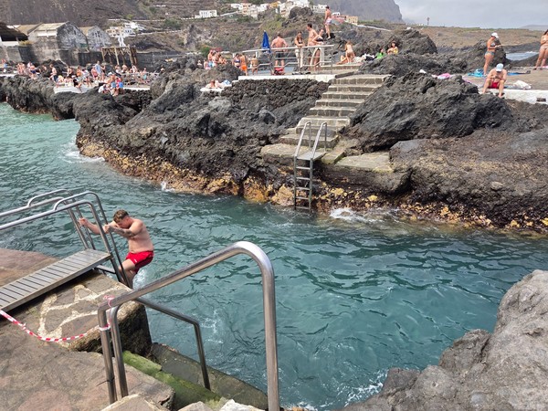 Charcos naturales de El Caletón en Garachico con bañistas disfrutando del agua cristalina entre las rocas.