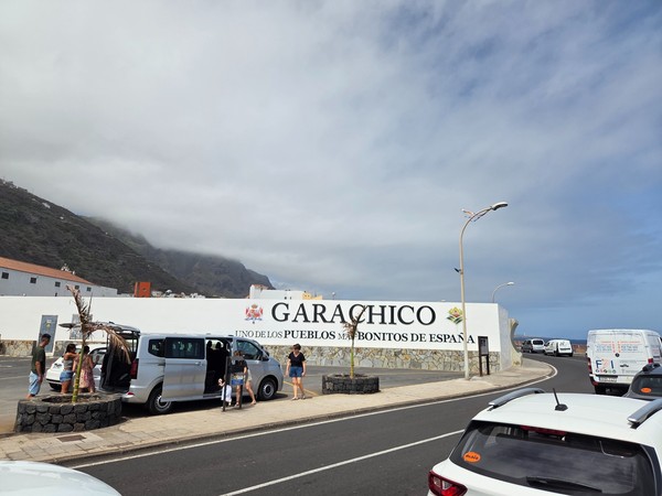 Entrada de Garachico, uno de los pueblos más bonitos de España, con vistas al mar y montañas nubladas al fondo.