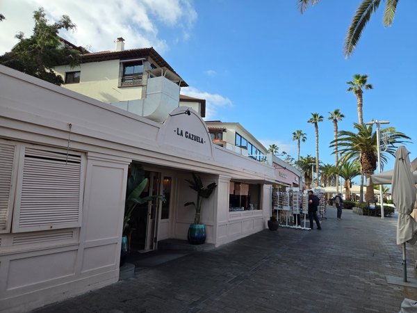 Fachada del restaurante La Cazuela en Puerto de la Cruz, situado en el paseo marítimo, con terrazas, palmeras y ambiente turístico.