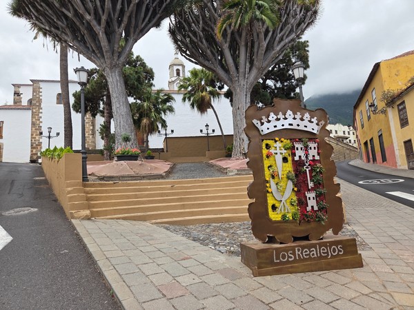 Centro histórico de Los Realejos con su iglesia, árboles centenarios y el escudo floral del municipio.
