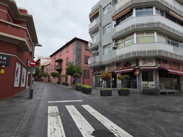 Calle tranquila del centro del Puerto de la Cruz con edificios modernos y casas tradicionales.